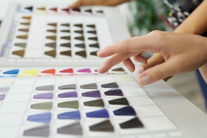woman choosing hair dye colour from catalog in beauty salon coloured hair at home